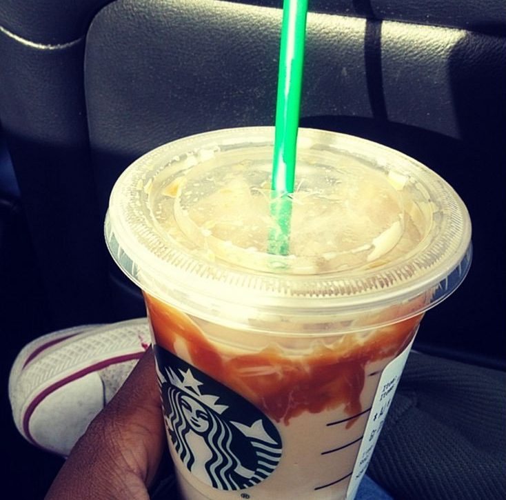 Foto de um copo da Starbucks sendo segurado por uma pessoa dentro de um carro
