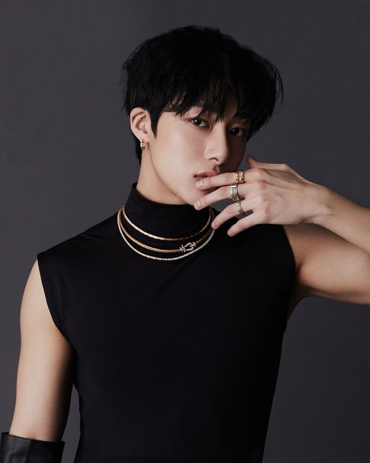 Integrante Hyungwon do MONSTA X vestindo camiseta de gola alta preta, usando acessórios no pescoço, mãos e orelhas