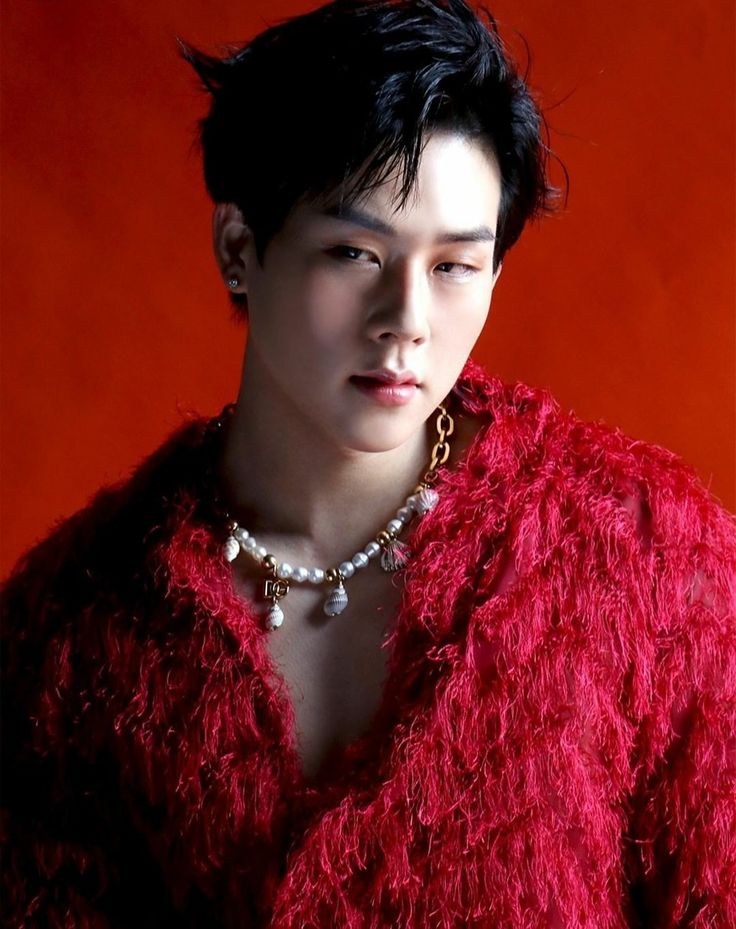 Foto de Jooheon do MONSTA X usando um casaco de pelos vermelho em fundo vermelho