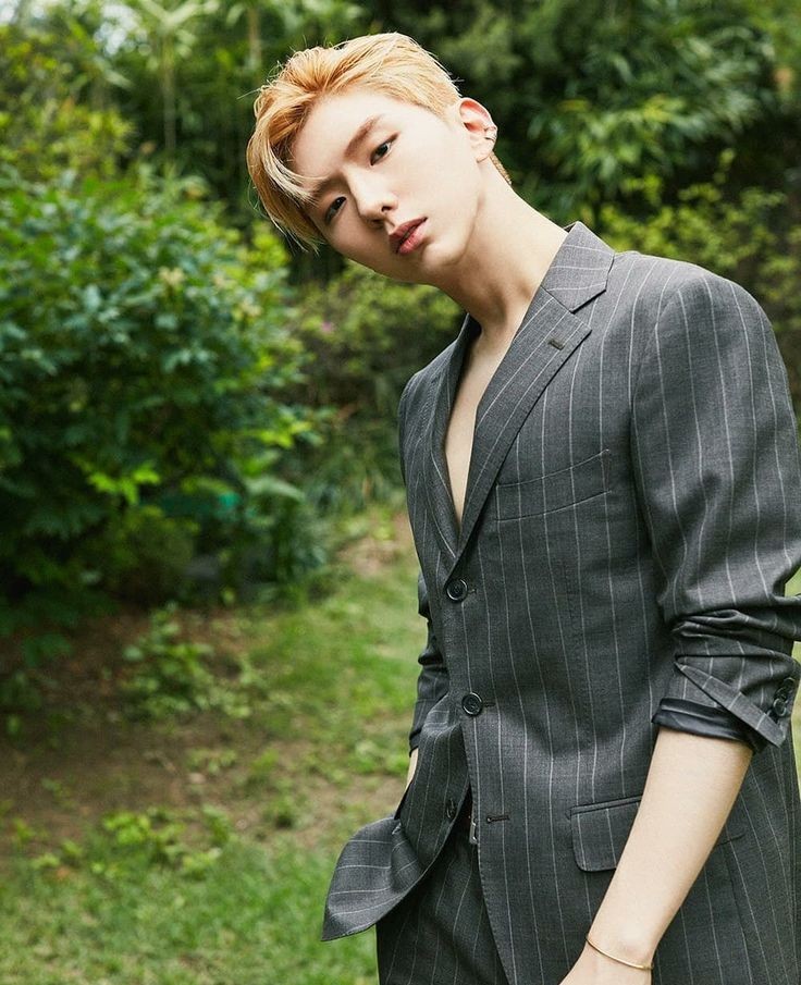 Integrante Kihyun do MONSTA X em paisagem verde vestindo trajes formais