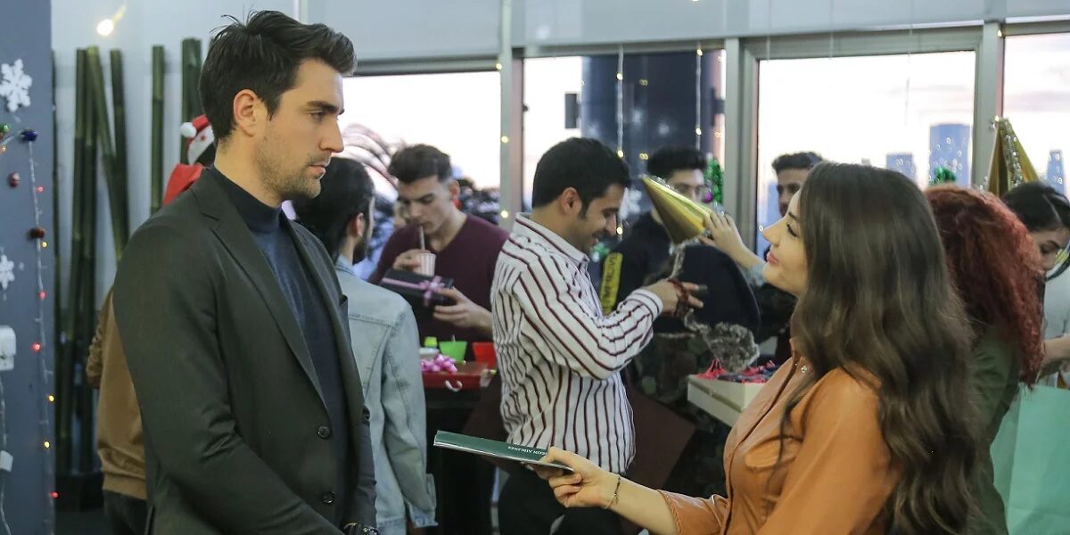 Cena de “Afili Aşk” em que os personagens trocam presentes, com decorações natalinas ao fundo.