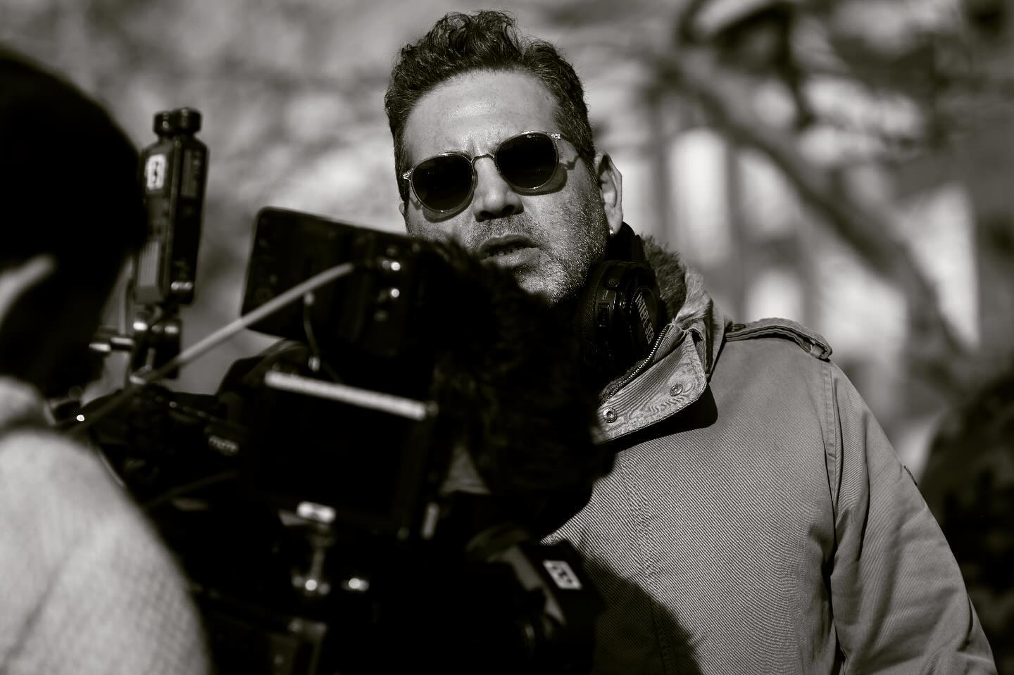 Foto em preto e branco do diretor Şenol Sönmez atrás de uma câmera.