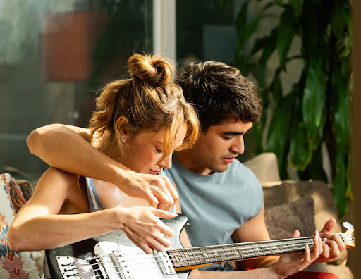 Miray Daner e Mert Ramazan tocando violão em cena de Bize Bi'şey Olmaz