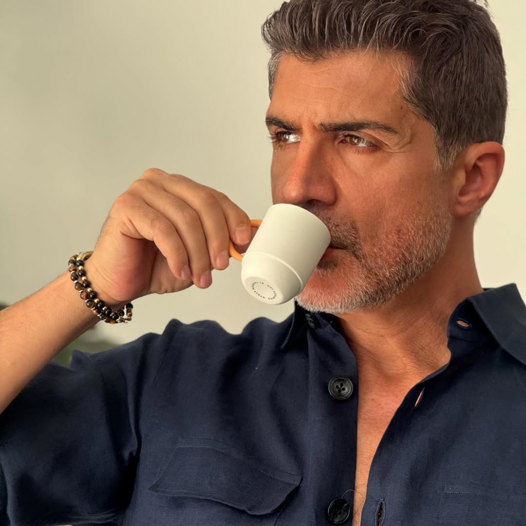 Özcan Deniz bebendo em uma xícara