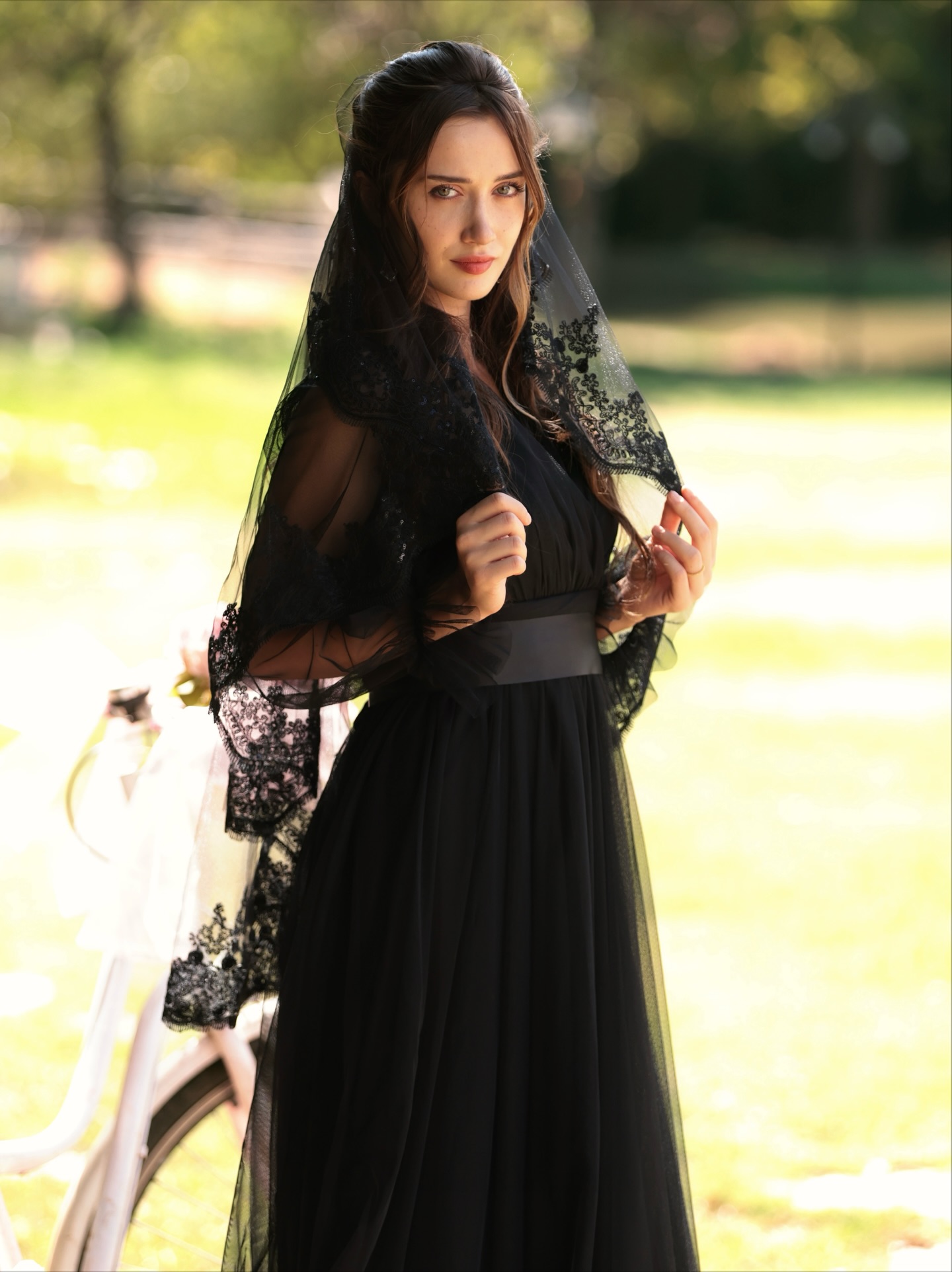 İlsu Demirci segurando um véu preto e usando um vestido preto.