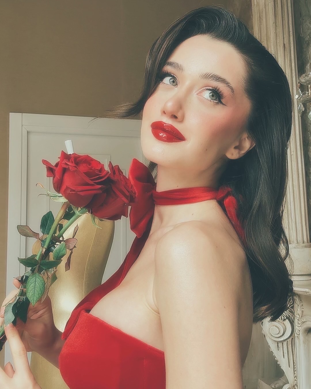İlsu Demirci segurando uma rosa vermelha enquanto usa um vestido vermelho.