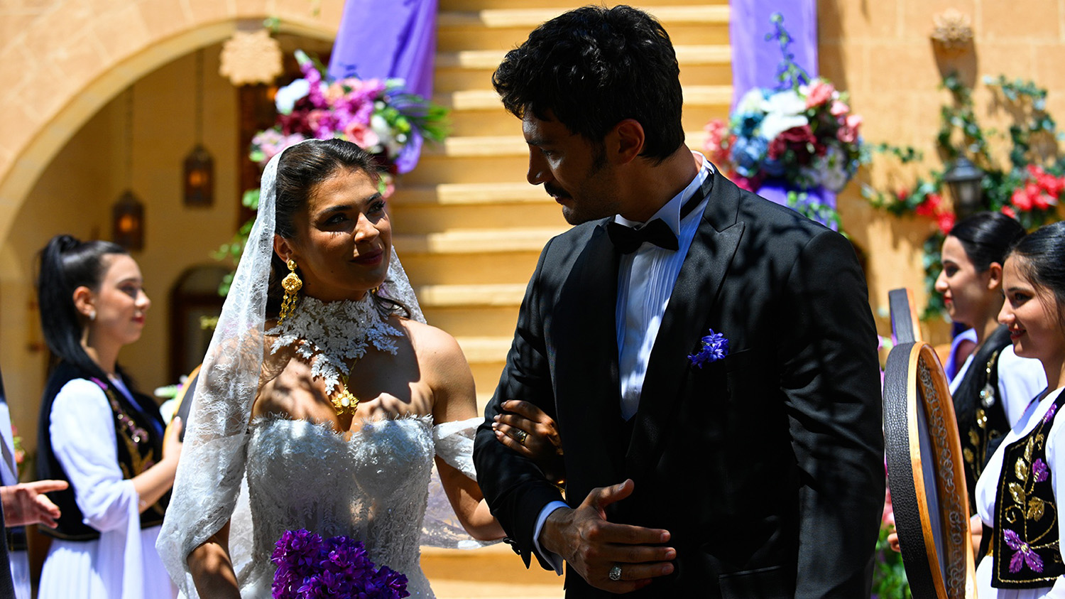 Cena do casamento dos personagens Serhat e Yıldız, com alguns atores ao fundo.