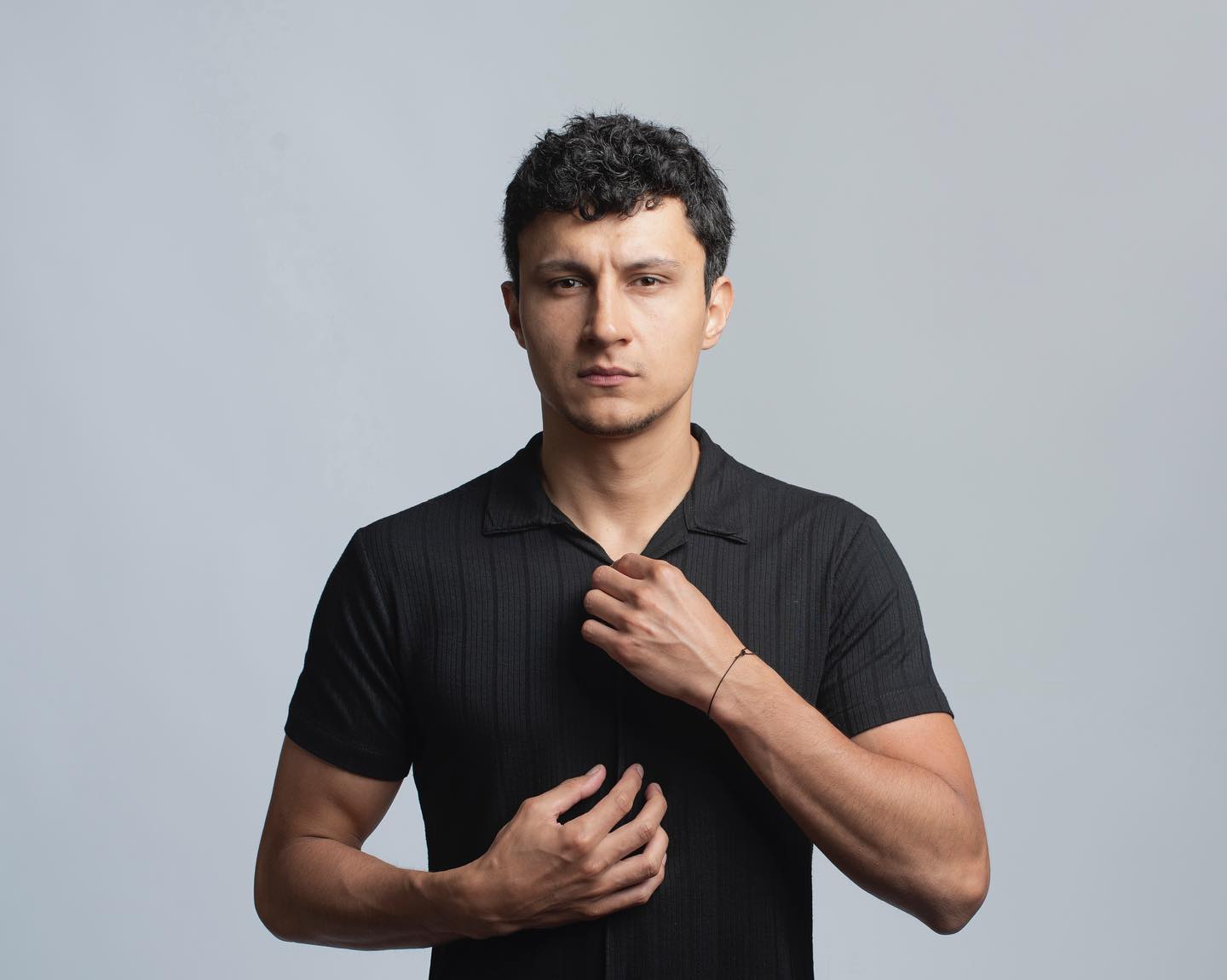 Alper Çankaya utilizando uma camisa polo preta enquanto posa para um retrato em estúdio, diante de um fundo cinza claro.