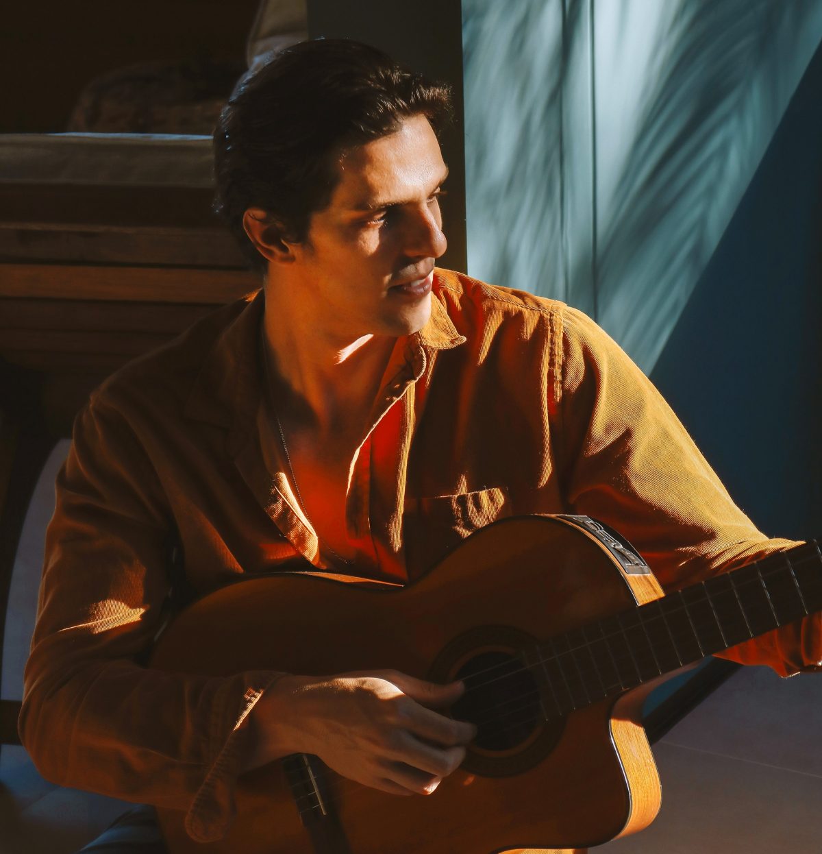 Rafael Infante aparece sentado tocando um violão.