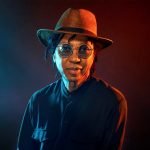 Djavan, de chápeu, sorrindo para foto