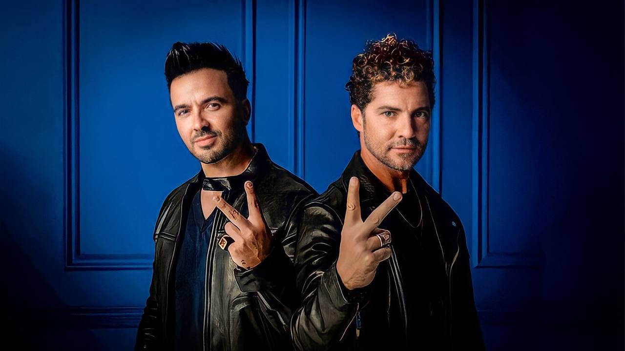 Luis Fonsi e David Bisbal aparecem juntos, com o sinal de 