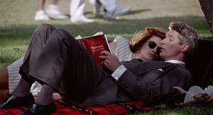 cena do filme "uma linda mulher" onde o homem está deitado na grama lendo e a mulher está deitada em cima dele