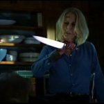 Atriz Jamie Lee Curtis no papel de Laurie Strood segurando e olhando para uma faca.
