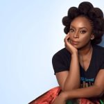 Chimamanda Adichie sentada com a mão no rosto em pose para foto