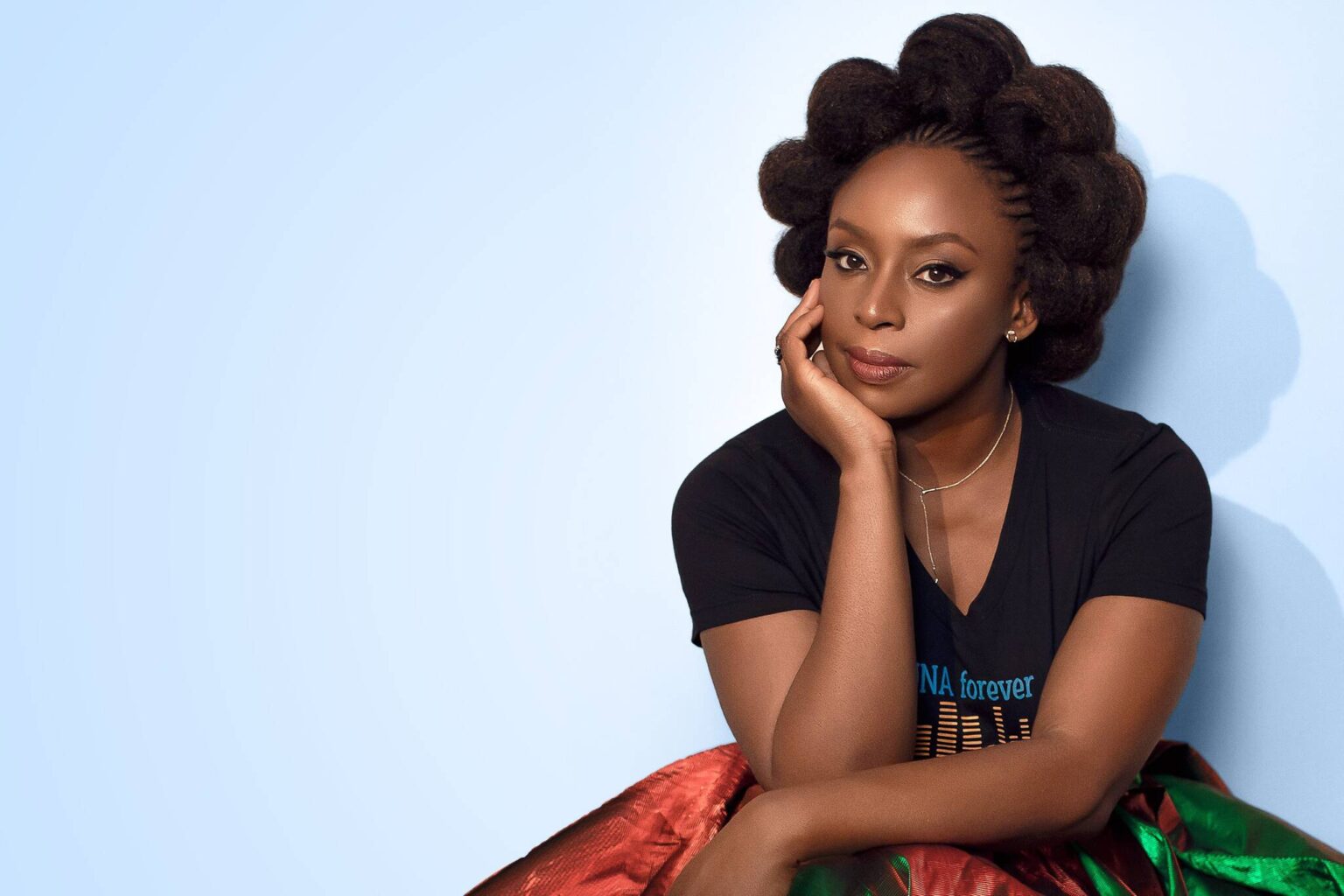 Chimamanda Adichie sentada com a mão no rosto em pose para foto