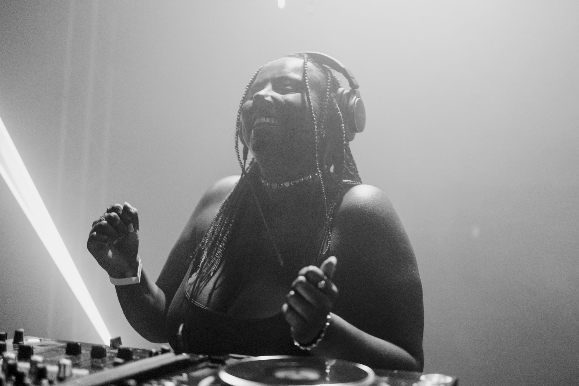 A imagem mostra a DJ Thais Queiroz tocando na noite