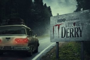 Carro passando por uma placa escrito "Bem vindos a Derry".