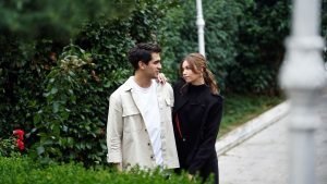 Seyran e Ferit caminham juntos por um jardim, trocando olhares.
