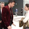 Kadir de terno vinho conversa com Meryem vestida de branco em frente a um edifício.
