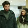 Engin Akyürek e Tuba Büyüküstün aparecem sorrindo e conversando em um ambiente interno durante uma cena da novela Kara Para Aşk.